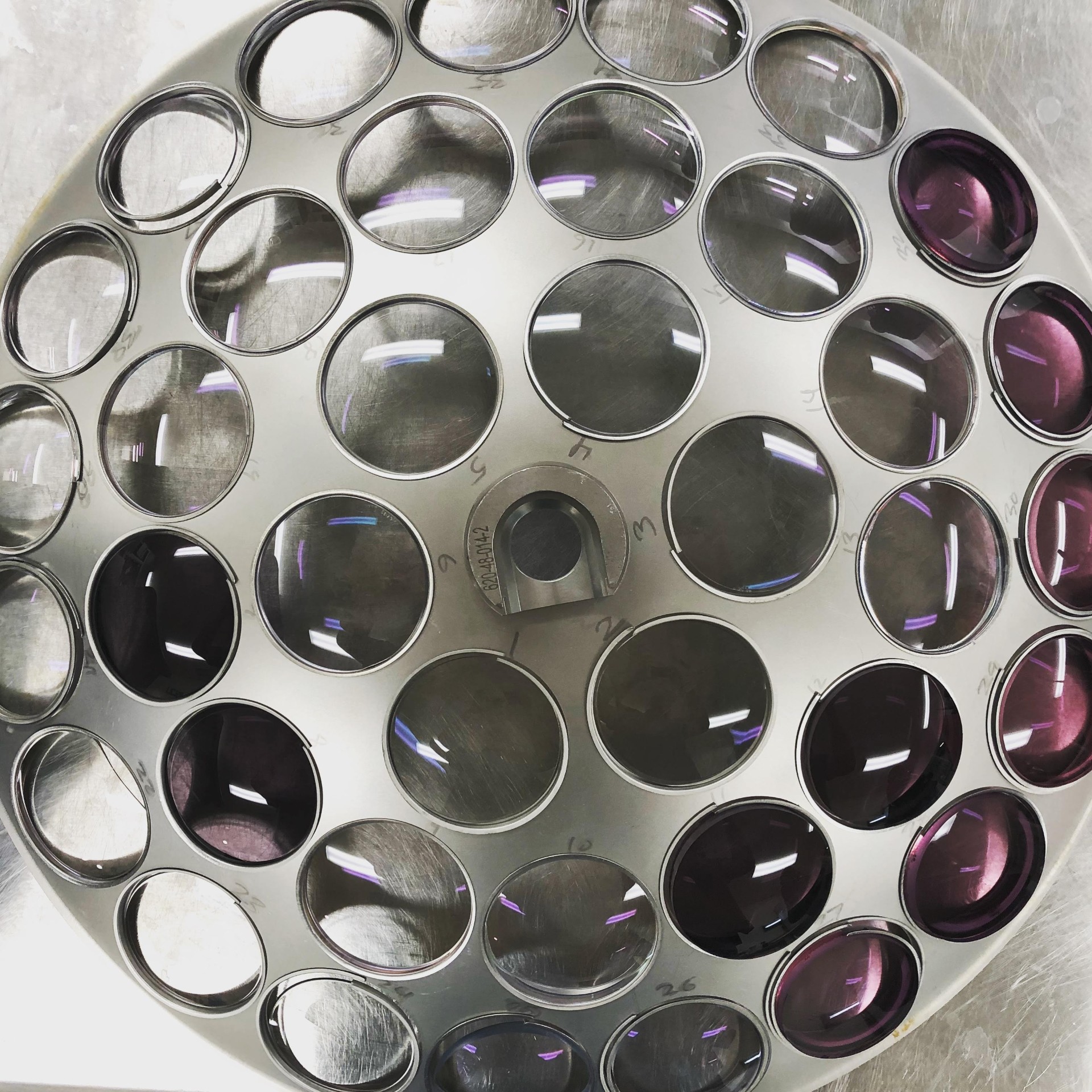 Lens tray with freshly AR-coated lenses showing characteristic purple residual reflection