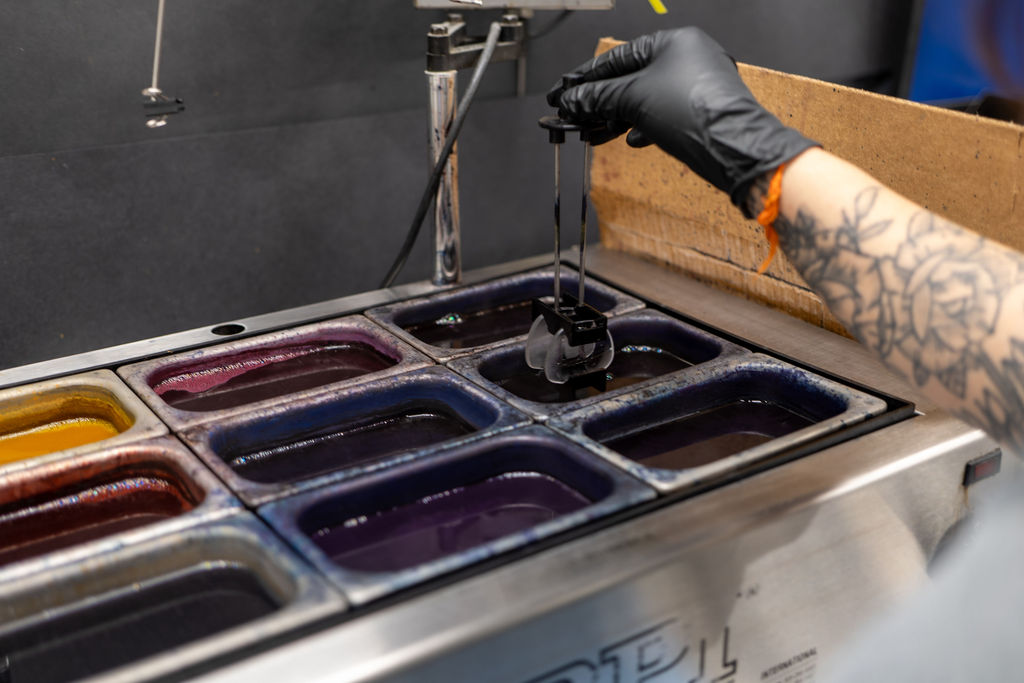 Premier Vision technician lowering a pair of lenses into a heated dye bath at the tint bar
